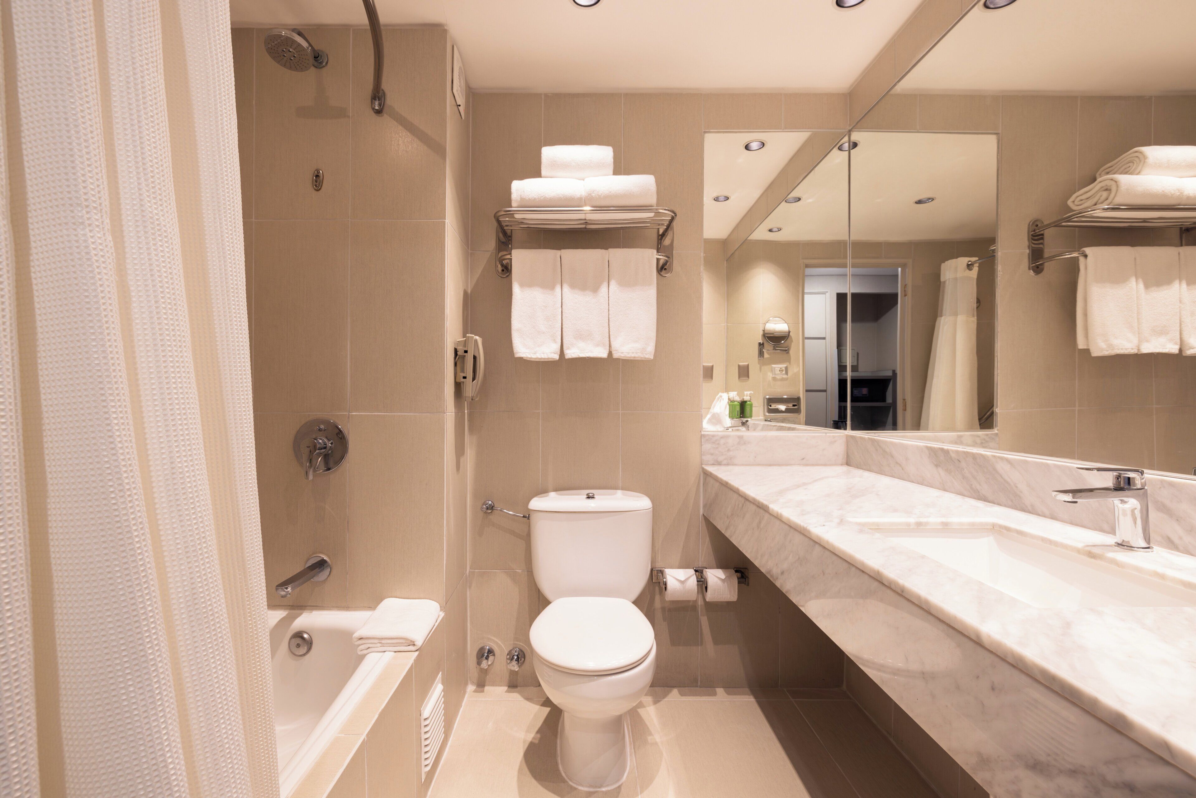Ein modernes Badezimmer mit Badewanne, Toilette und einem großen Spiegel.