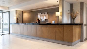 A modern reception desk with a wooden finish, a glass door entrance, and a wall-mounted sign.