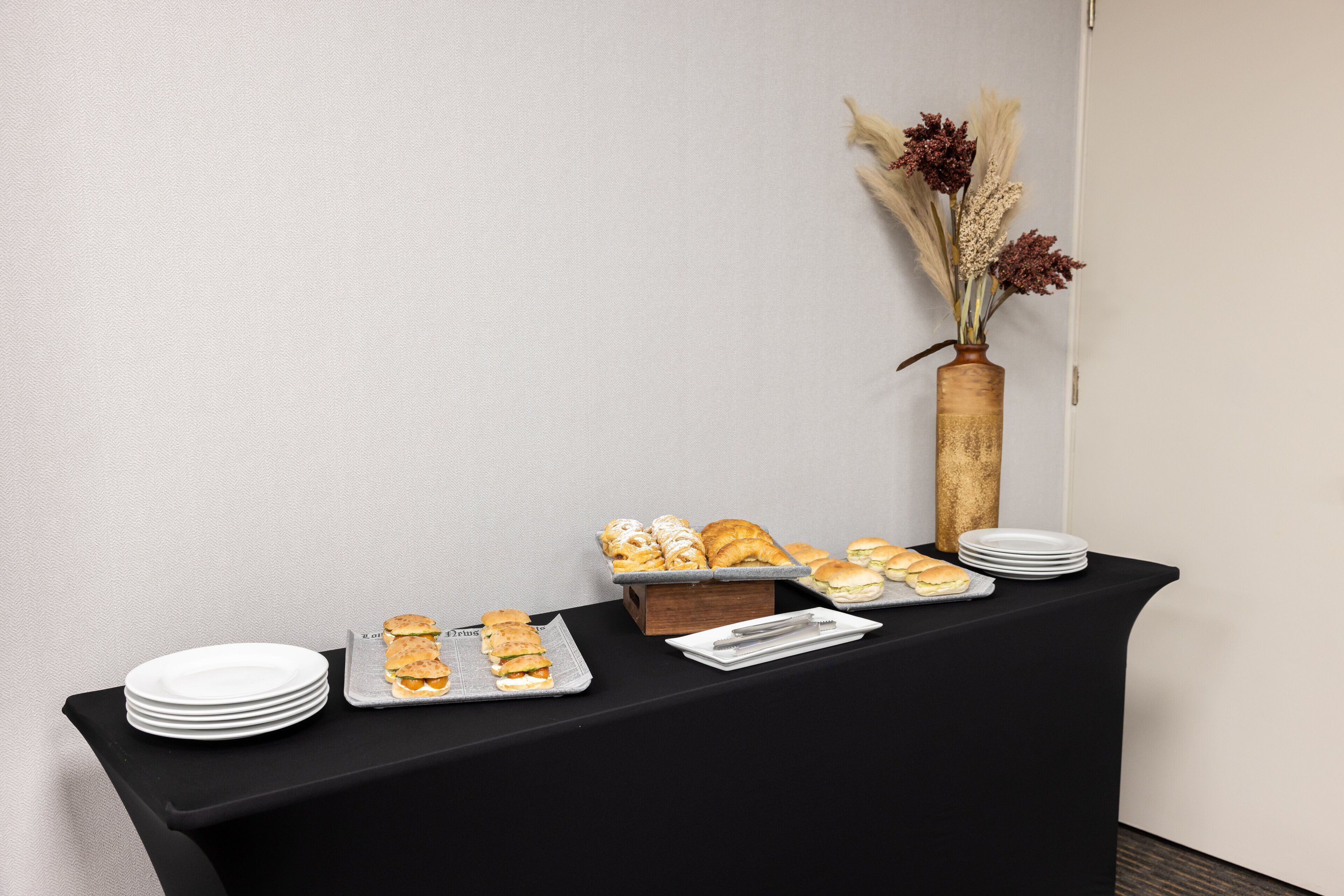 Une table de buffet garnie de divers plats et un vase rempli de fleurs séchées.