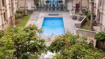 Piscina rodeada de follaje y equipo de ejercicios.