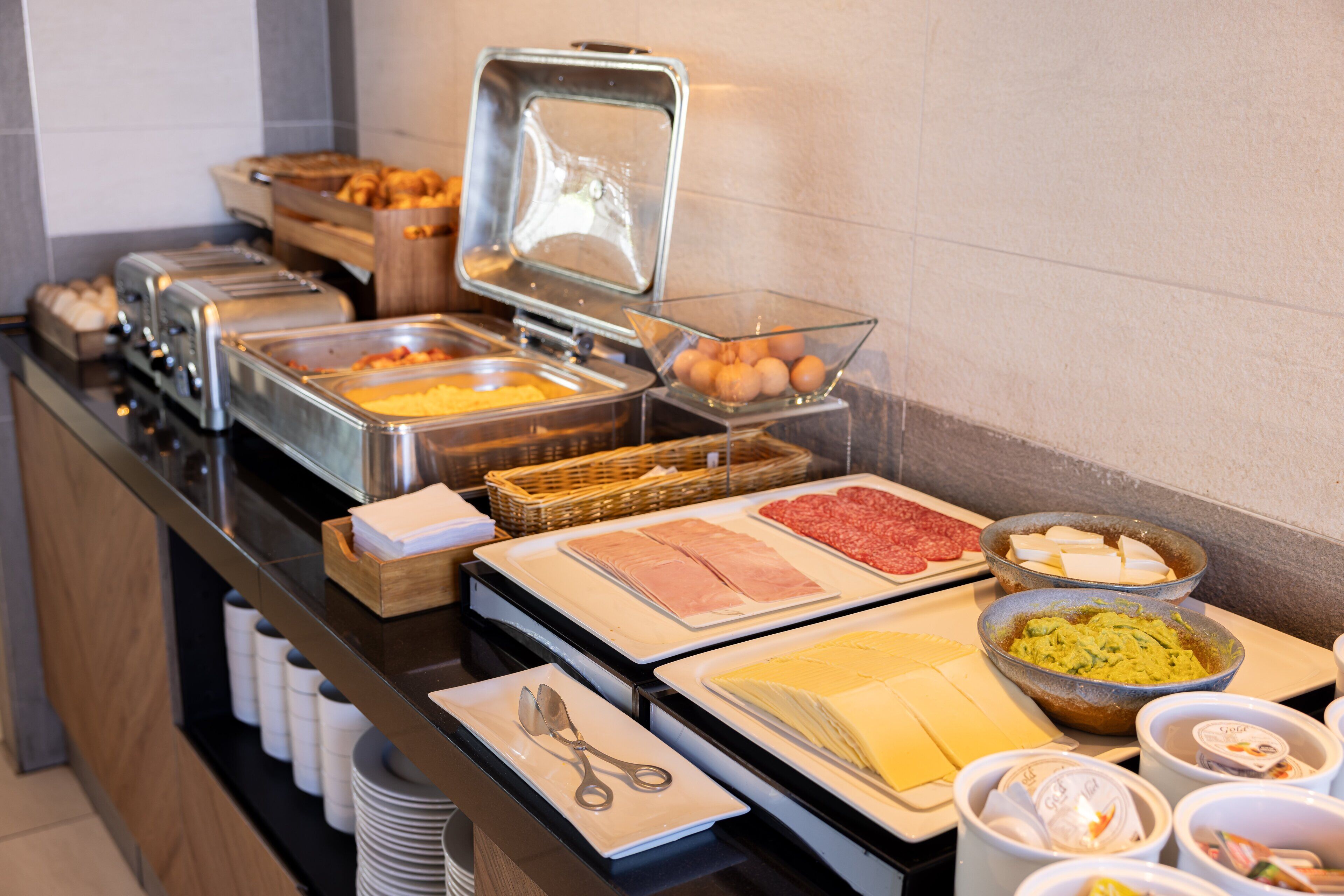 A buffet with various food items including meats, cheeses, and eggs.