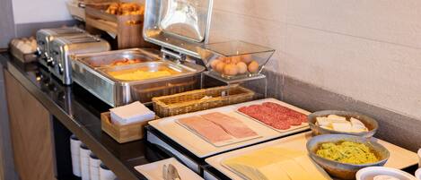 A buffet with various food items including meats, cheeses, and eggs.