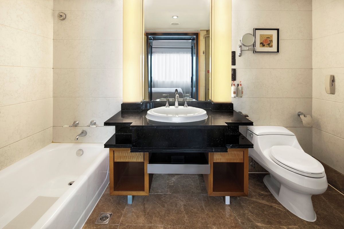 A modern bathroom with a bathtub, a sink with a mirror, and a toilet.