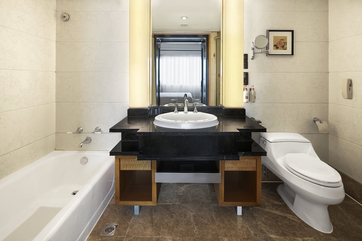 A modern bathroom with a bathtub, a sink with a mirror, and a toilet.