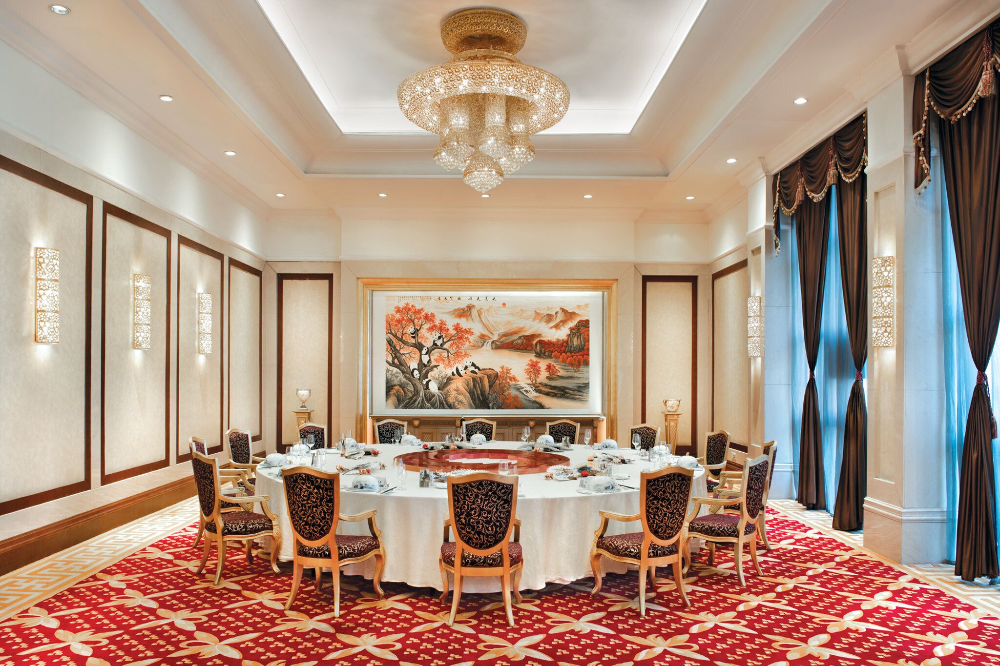 Un comedor formal con una gran mesa redonda, sillas y una araña.