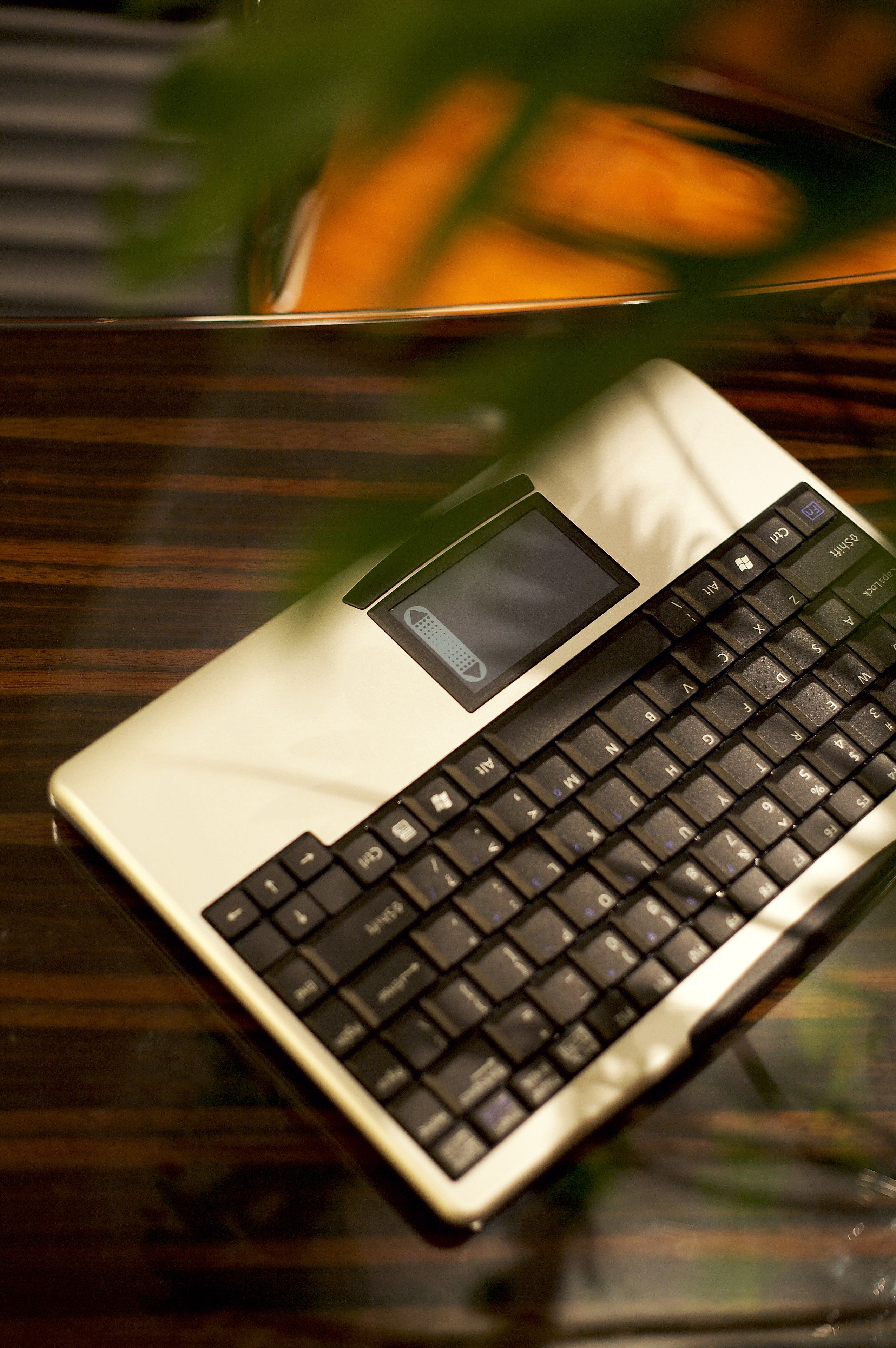 Un ordinateur portable posé sur une surface en bois, avec un clavier et un petit écran.