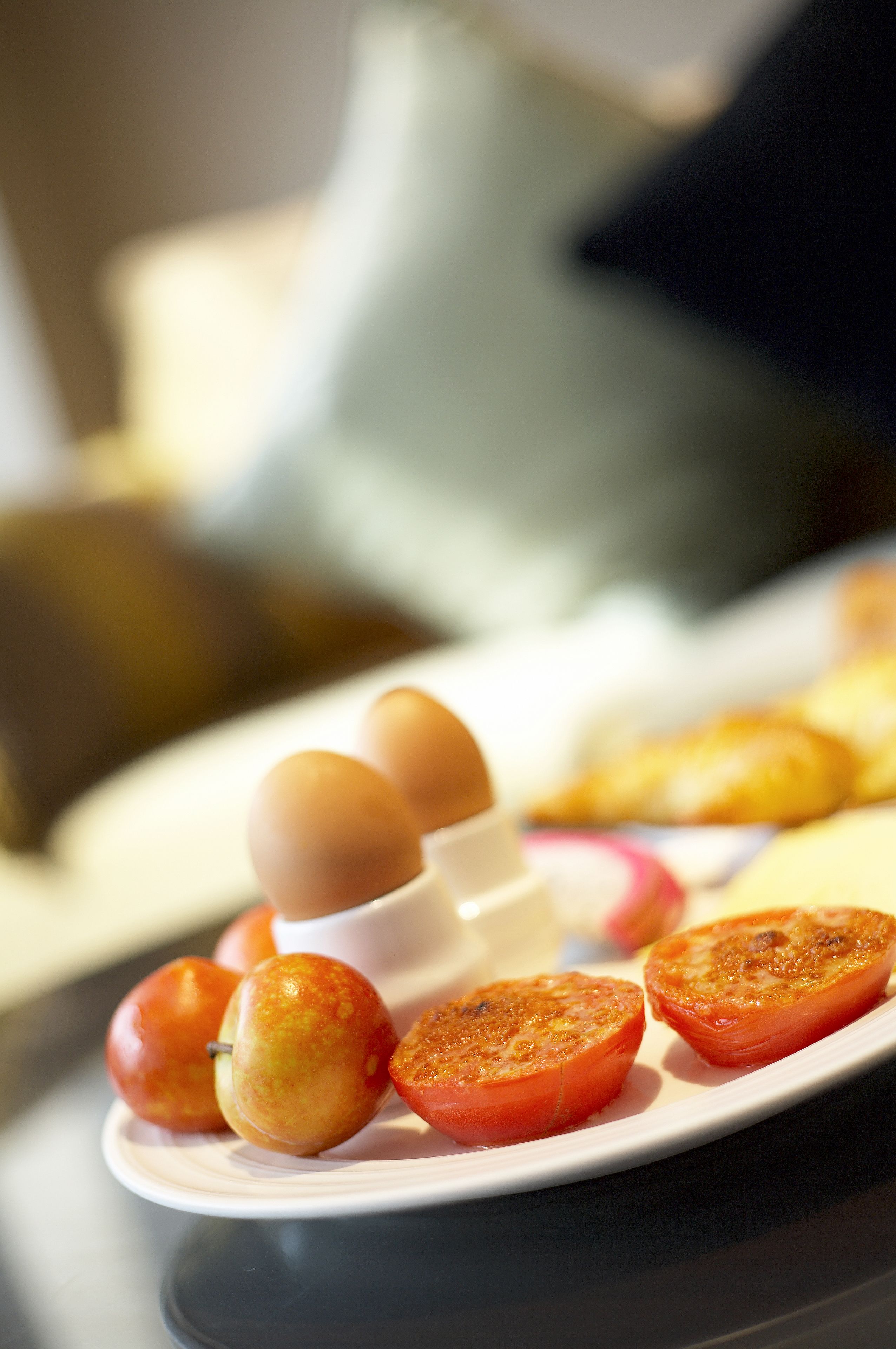 A plate with sliced tomatoes and eggs on a table.