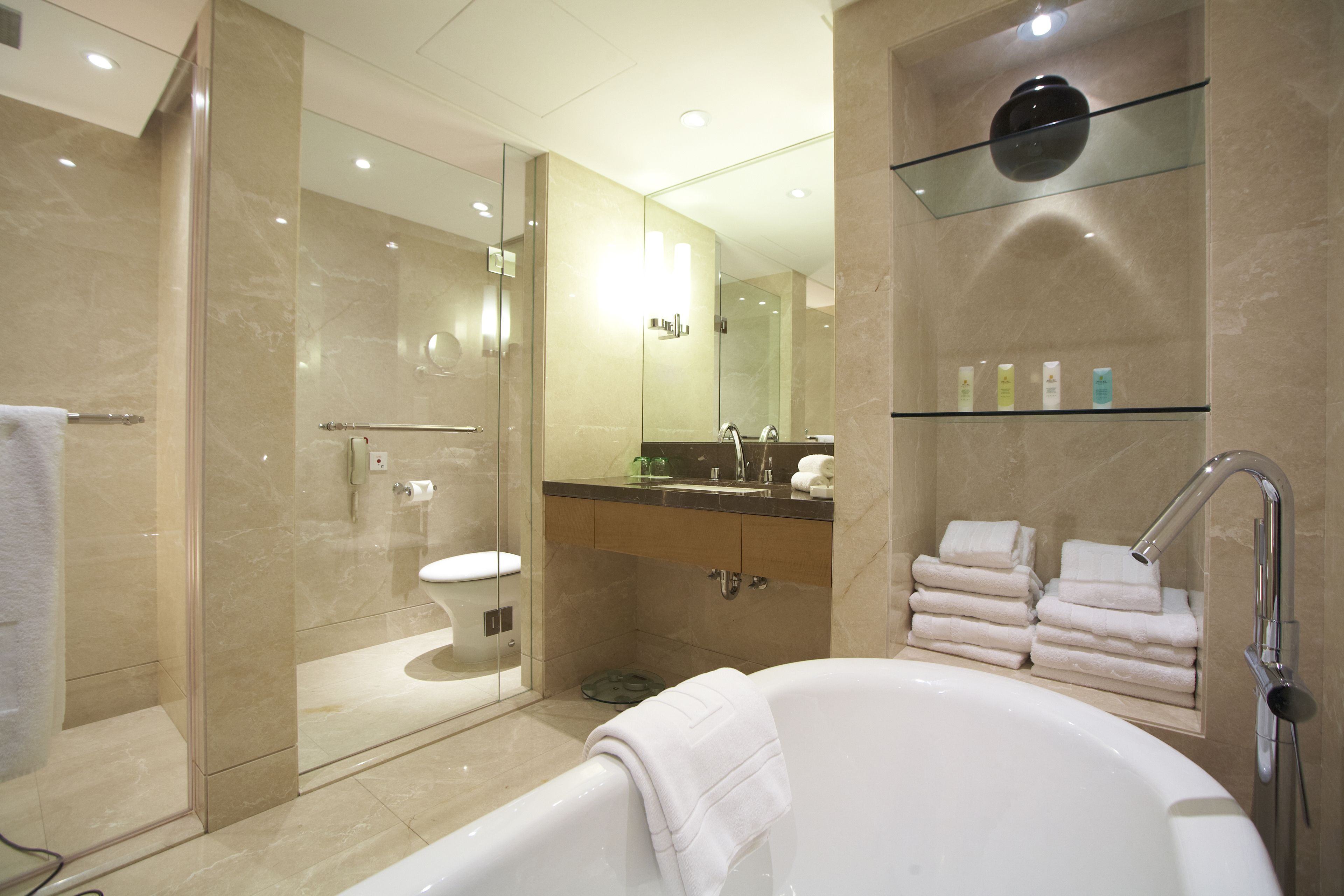 A modern bathroom with a glass-enclosed shower, a large bathtub, and a vanity with a mirror and shelves.