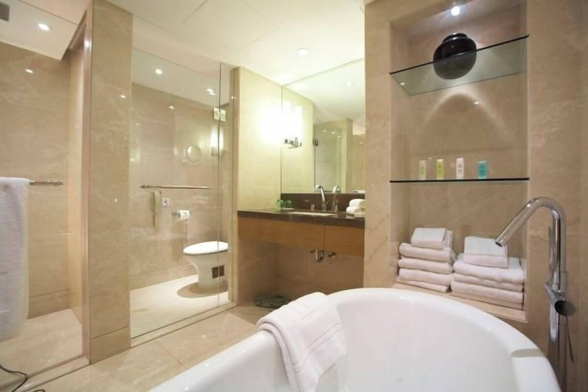 A modern bathroom with a glass-enclosed shower, a large bathtub, and a vanity with a mirror and shelves for toiletries.