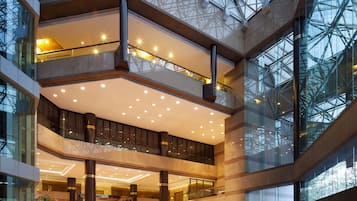 Ein mehrgeschossiges Atrium mit Glasgeländern, einer zentralen Fontäne und einem polierten Boden.