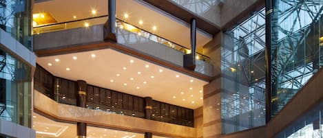A multi-level atrium with glass railings, a central fountain, and a polished floor.
