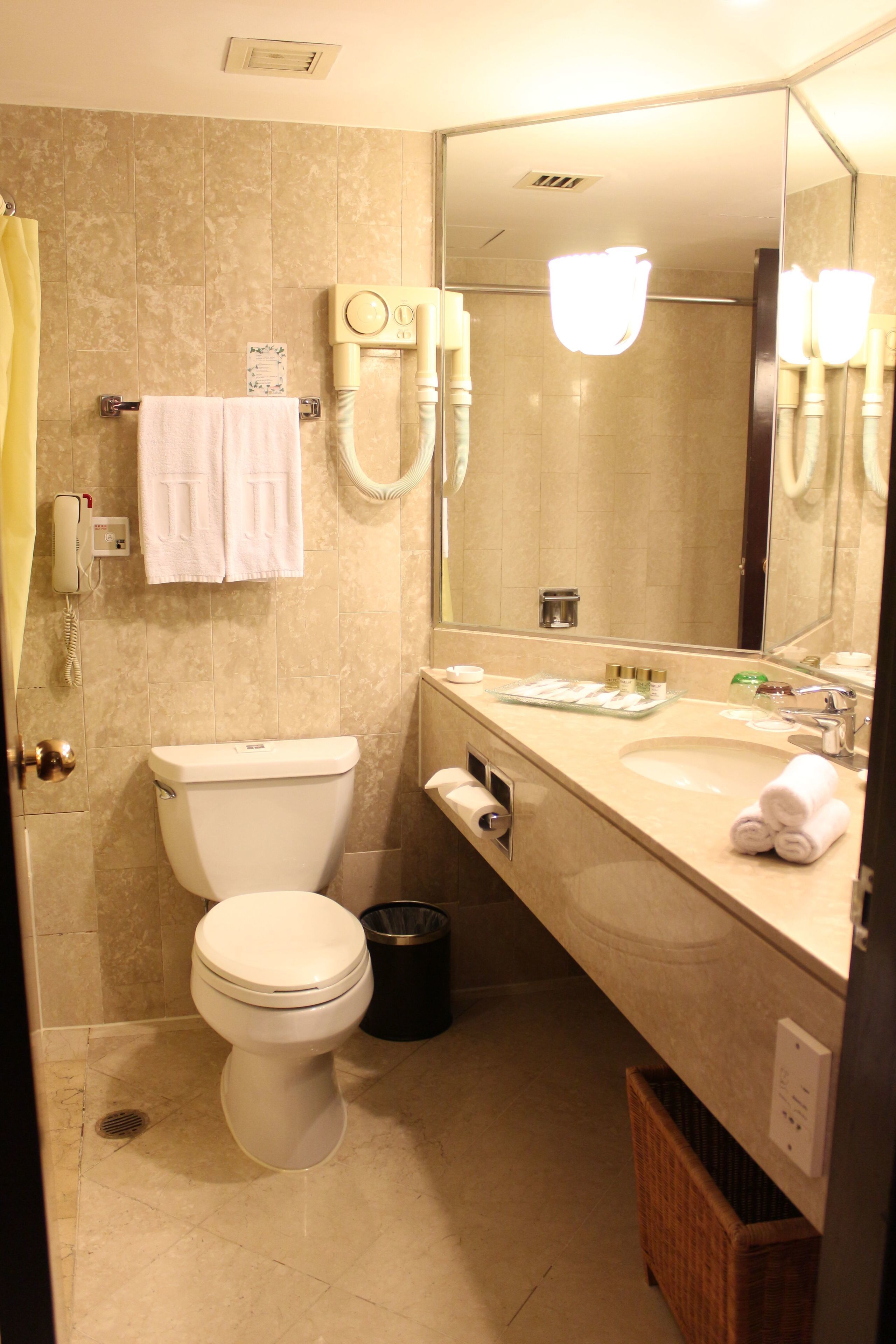 A bathroom with a toilet, sink, mirror, and towel rack.