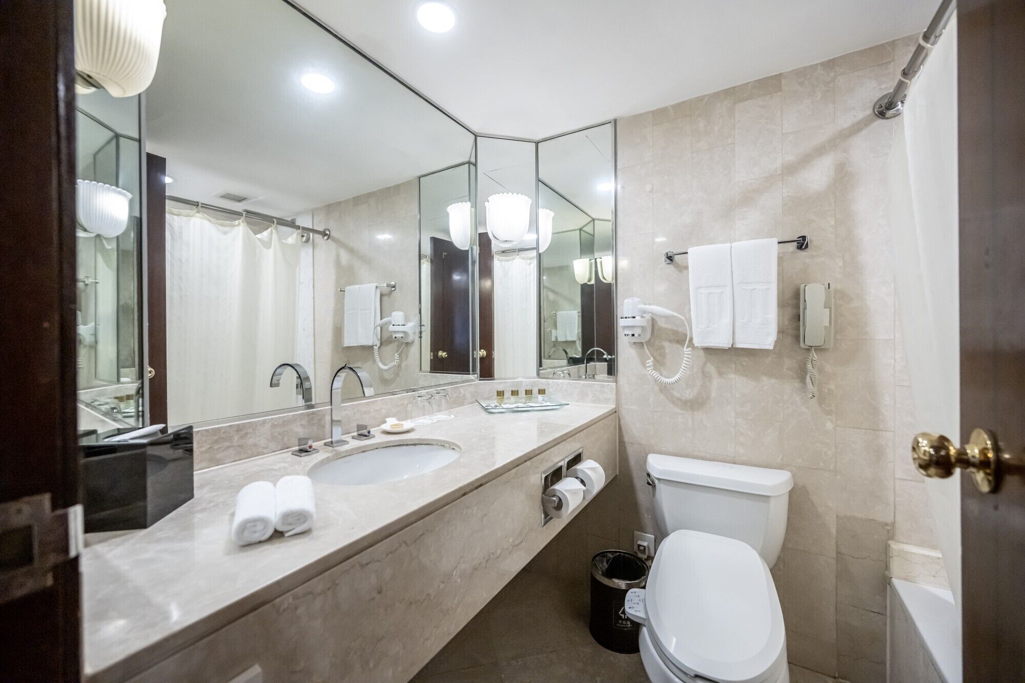 A modern bathroom with a double sink, a toilet, and a large mirror.