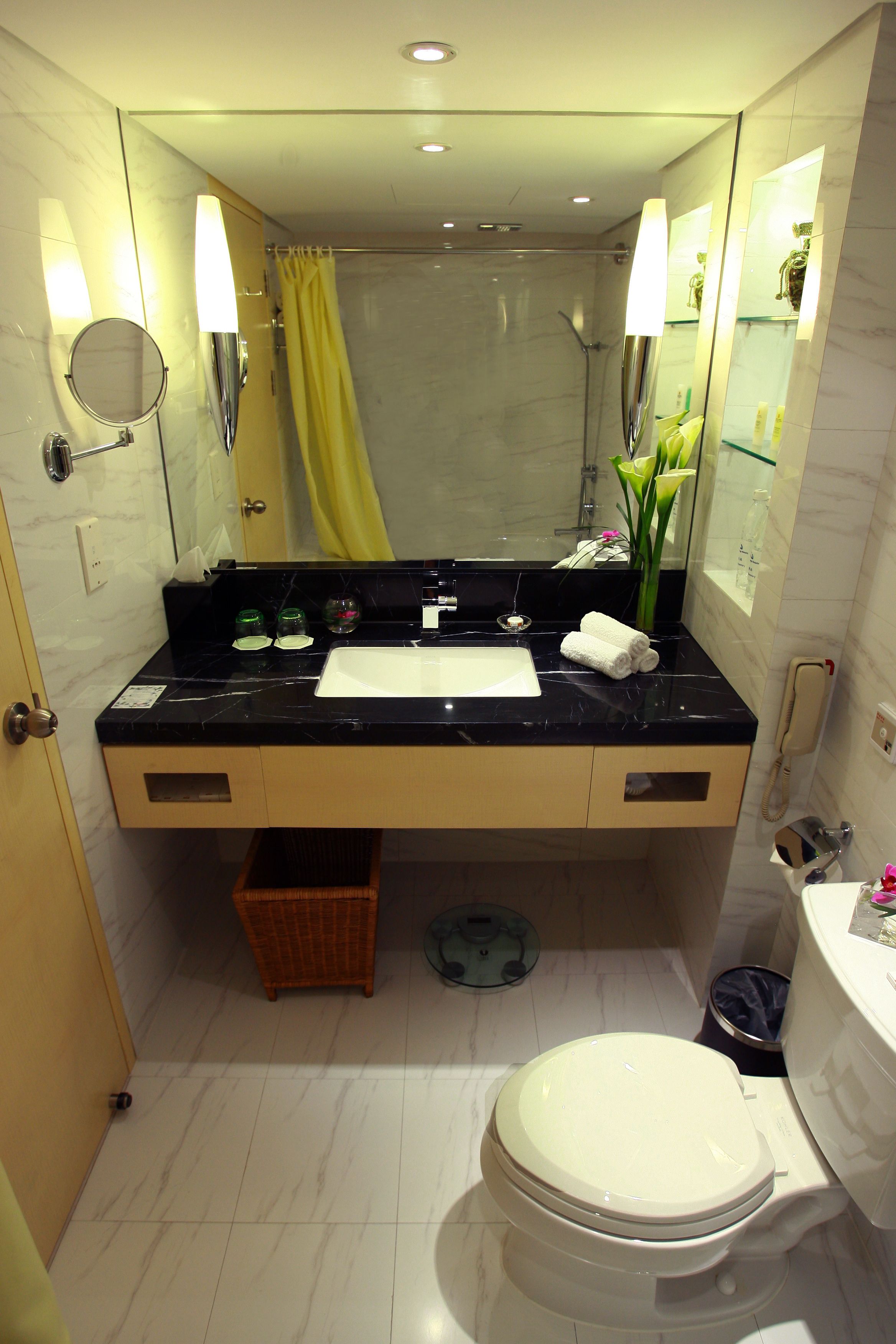 Een moderne badkamer met een marmeren wastafel, toilet en douche.