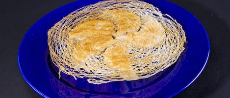 A blue plate with a golden-brown food item, possibly a dessert, on a dark background.
