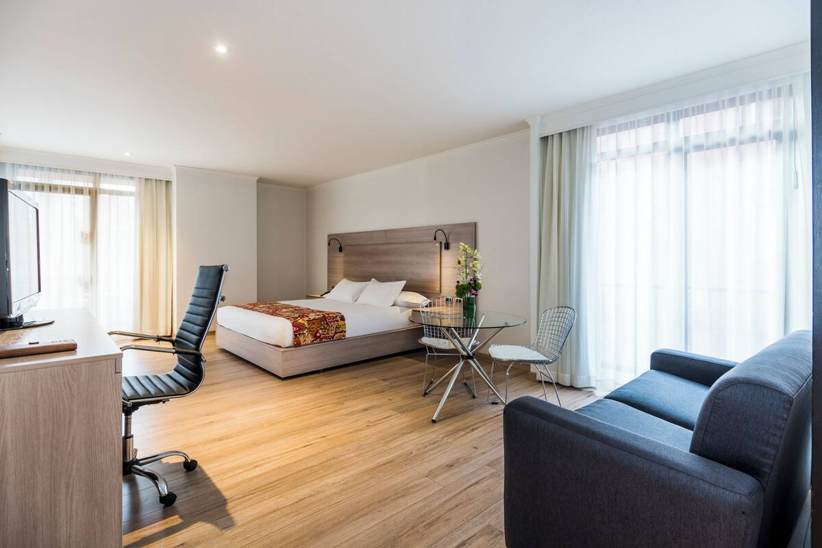 Une chambre d’hôtel comprenant un lit, un bureau, une chaise, un canapé et une petite table.