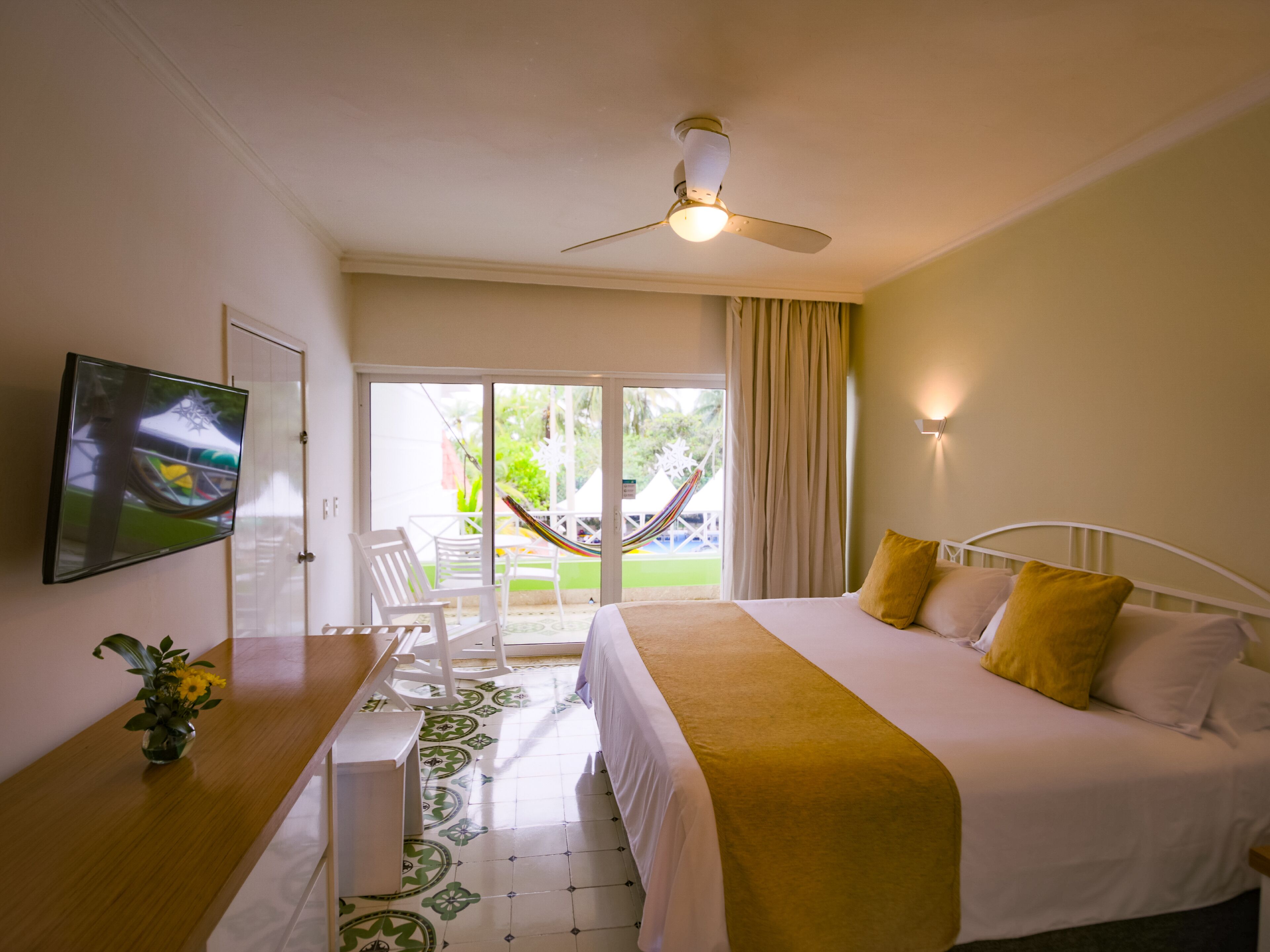 A hotel room with a bed, a desk, a chair, a television, and a view of the outdoors.