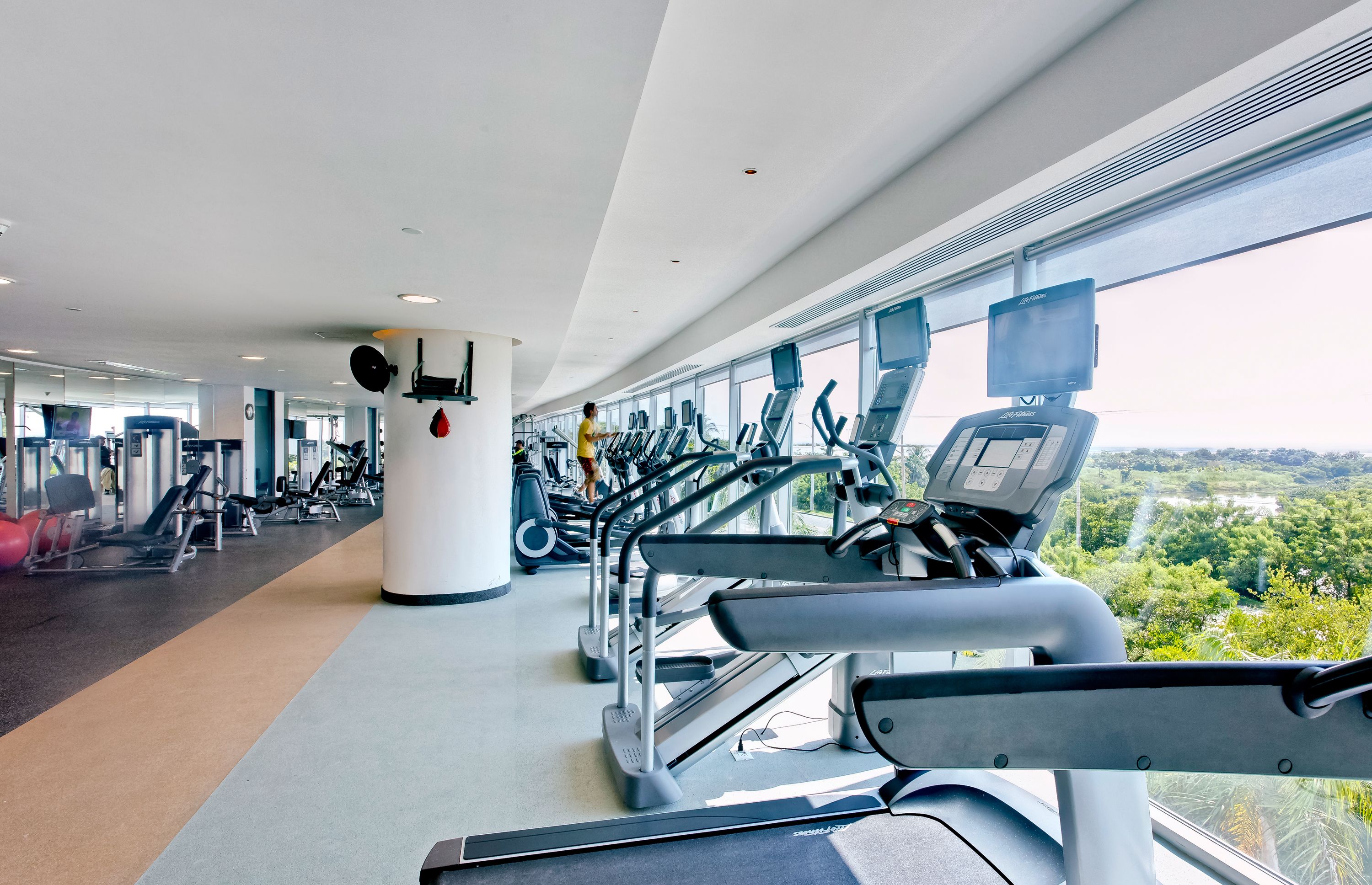 Une salle de sport équipée de tapis de course, de vélos d’exercice et d’appareils de musculation.