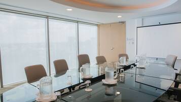 Un salón de conferencias con una mesa de vidrio, sillas y una pizarra.