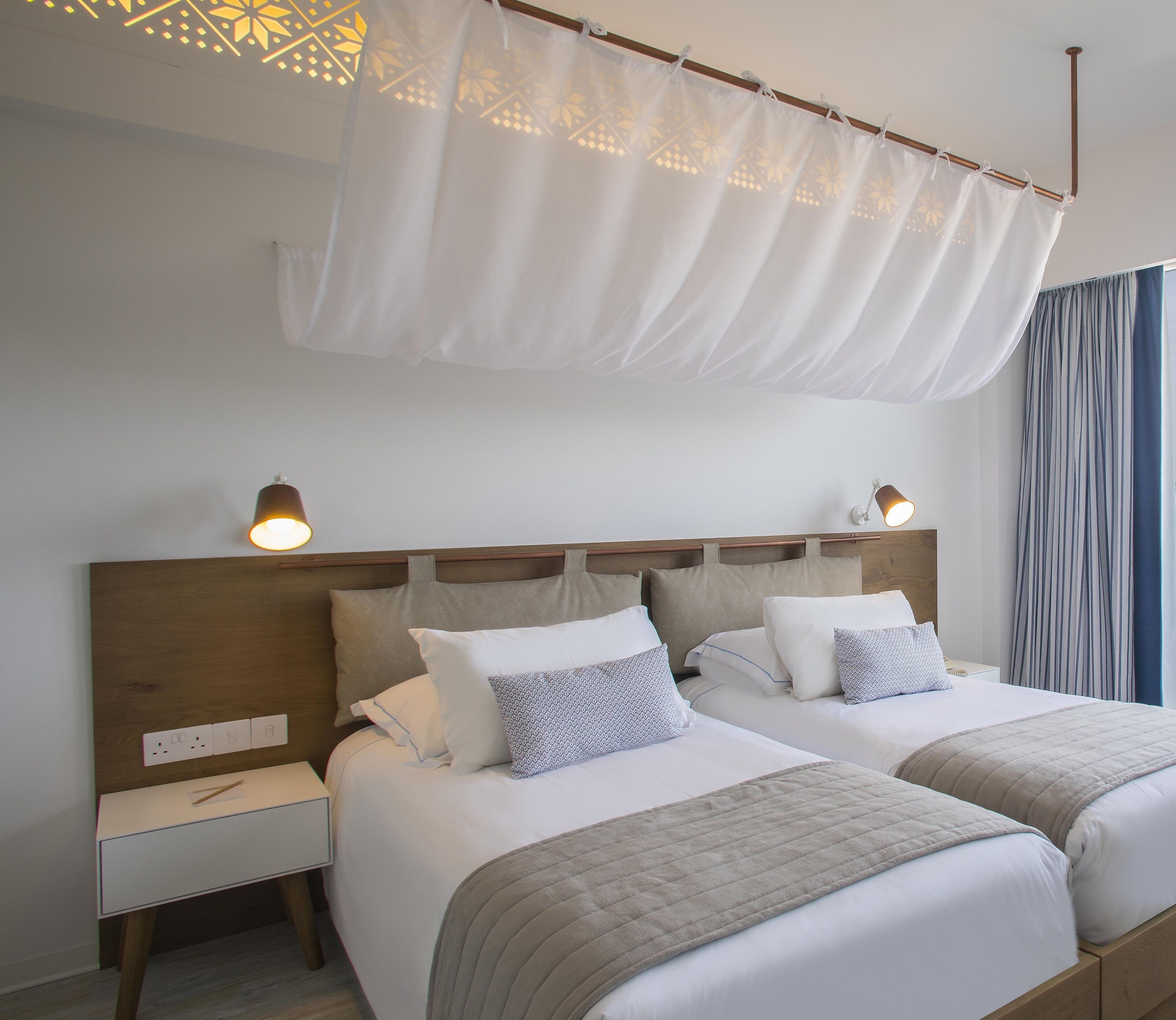 A double bed with a wooden headboard, two bedside tables, and a canopy overhead.