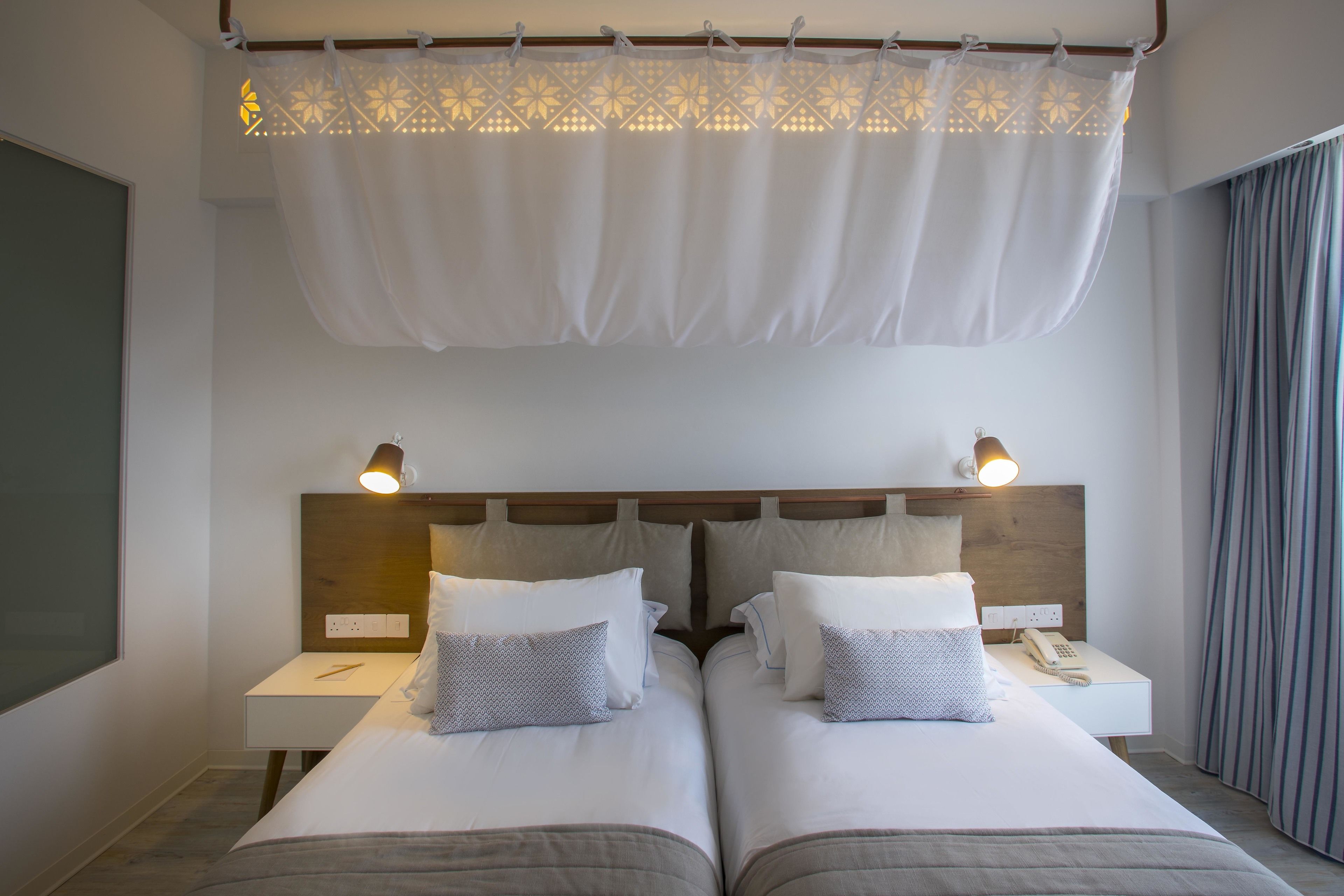 A double bed with two bedside tables, each with a lamp and a phone.