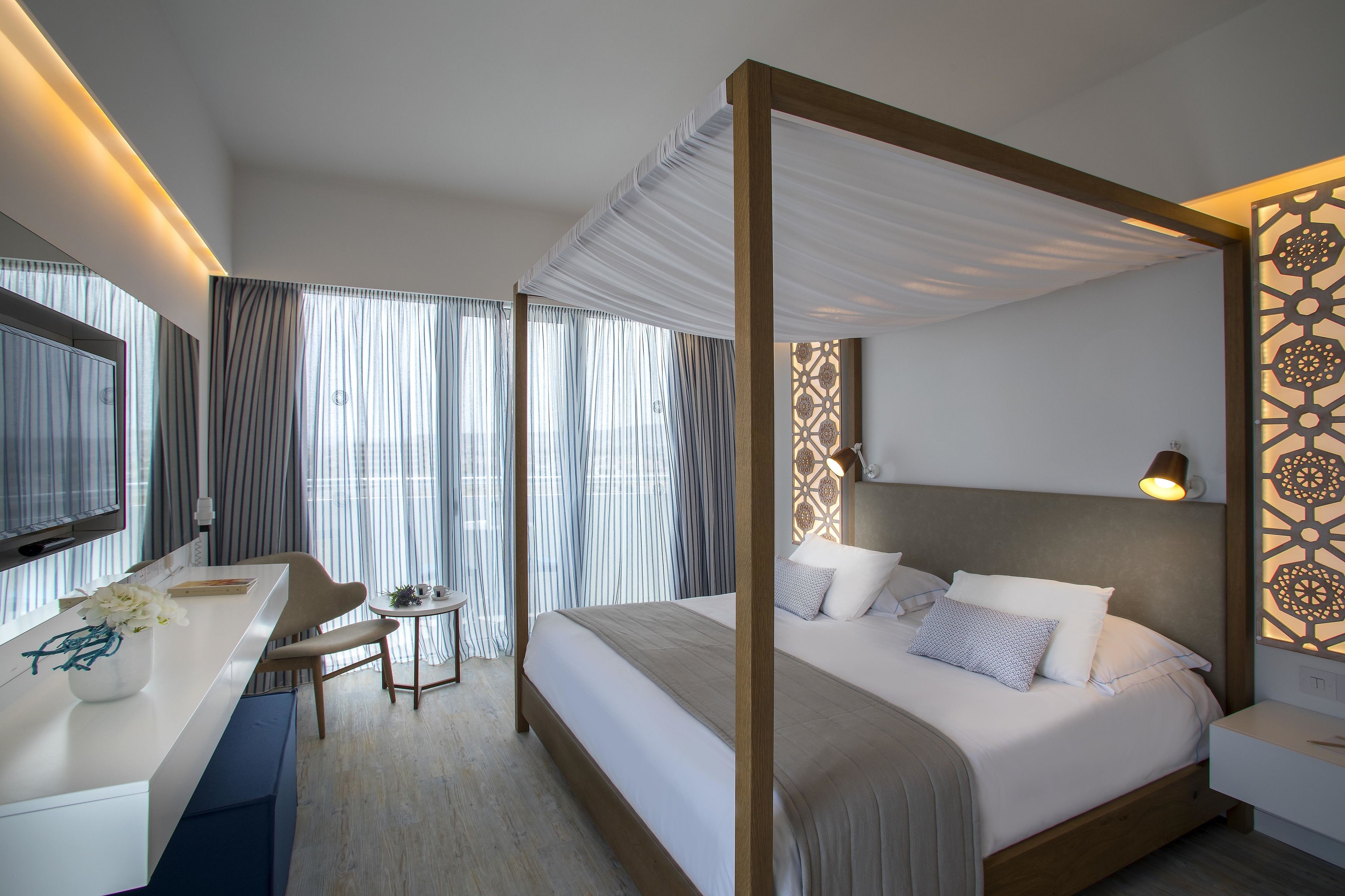 A modern hotel room with a large bed, a desk, and a chair.