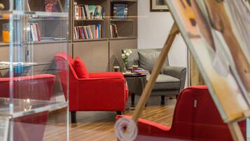Una sala de estar moderna con muebles rojos y grises, una estantería y un cuadro en la pared.