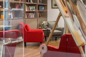 Ein modernes Wohnzimmer mit roten und grauen Möbeln, einem Bücherregal und einem Gemälde an der Wand.