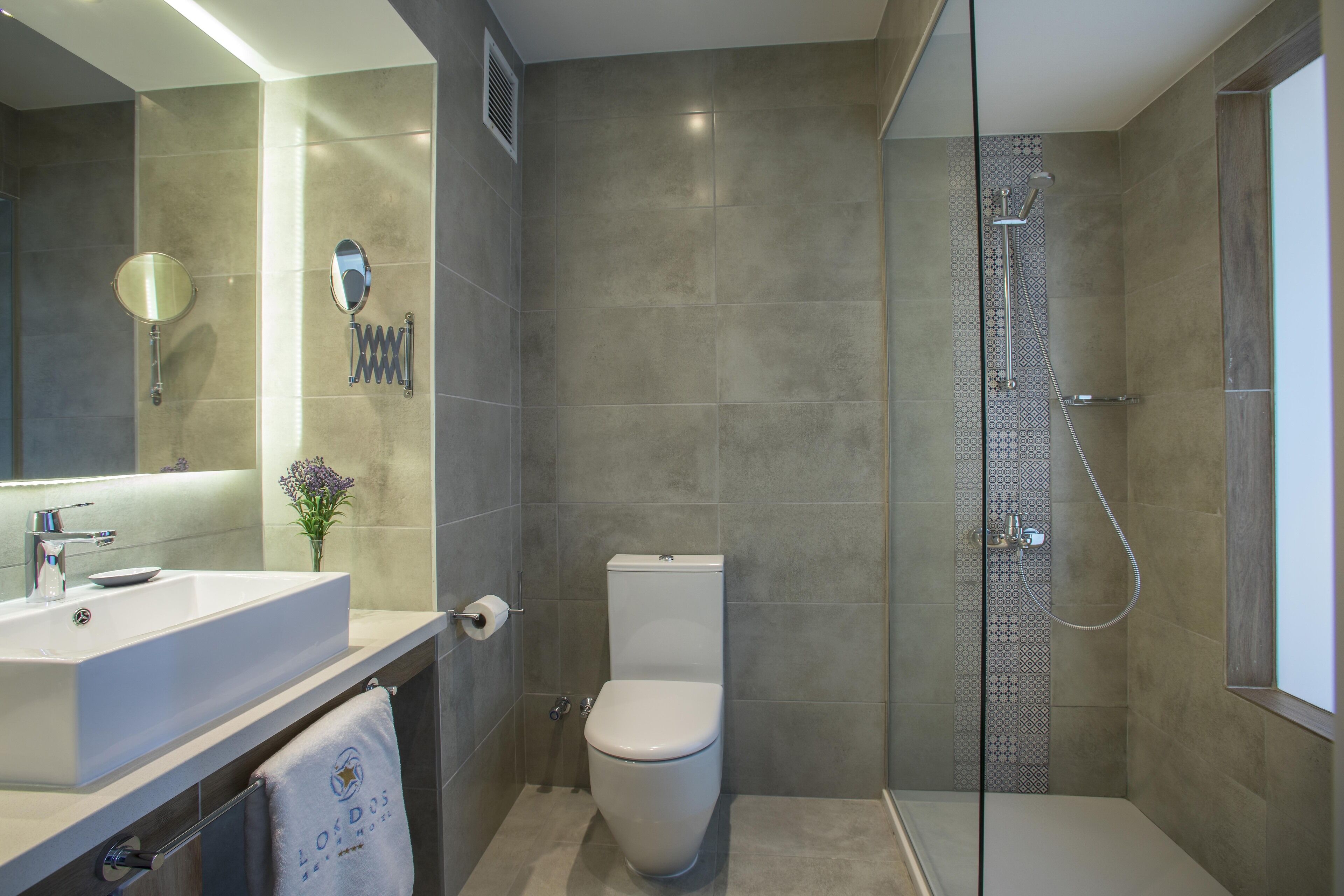A modern bathroom with a large mirror, a sink, a toilet, and a shower area.