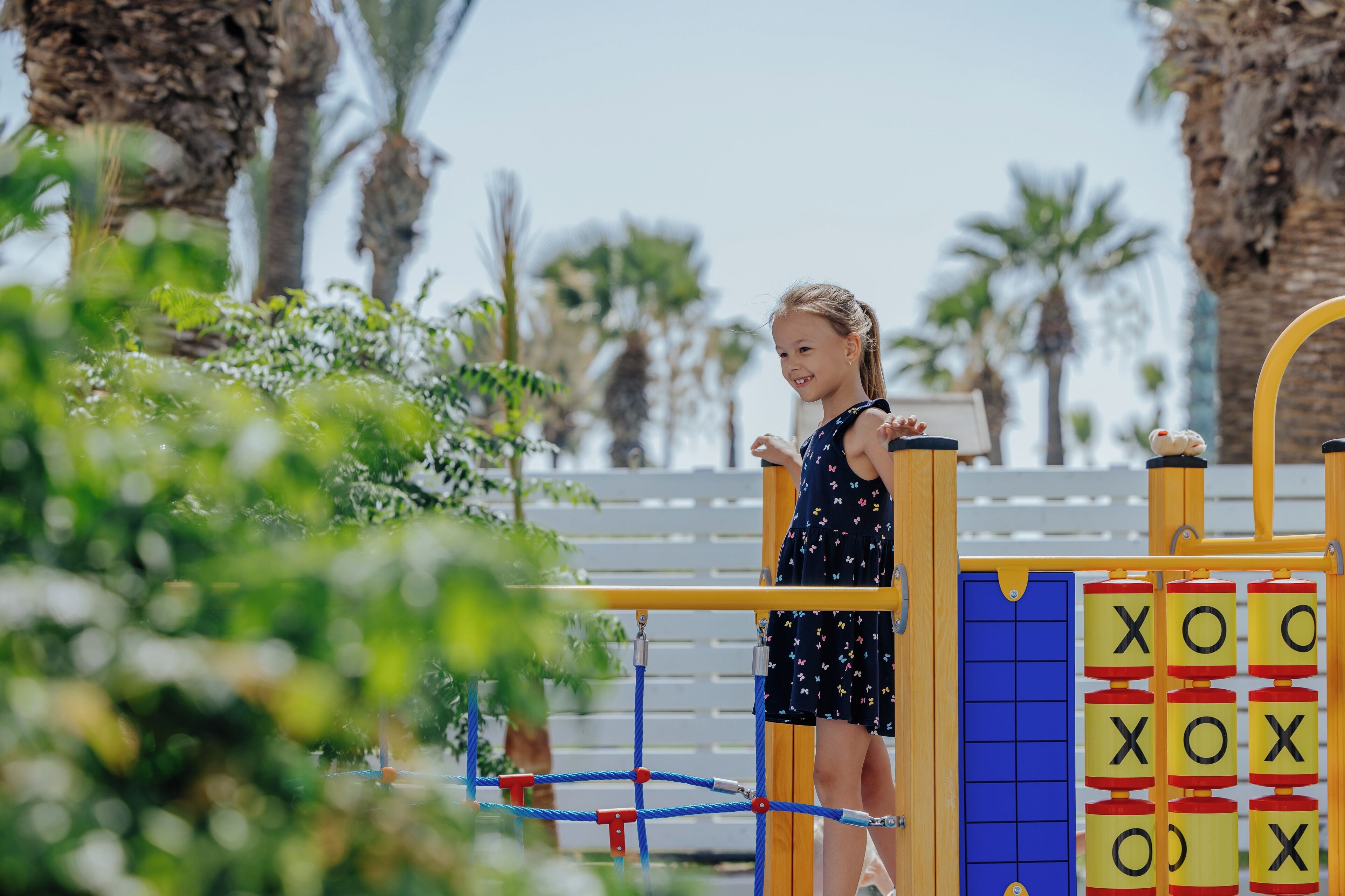 A child playing on a playground with a slide and climbing structure.