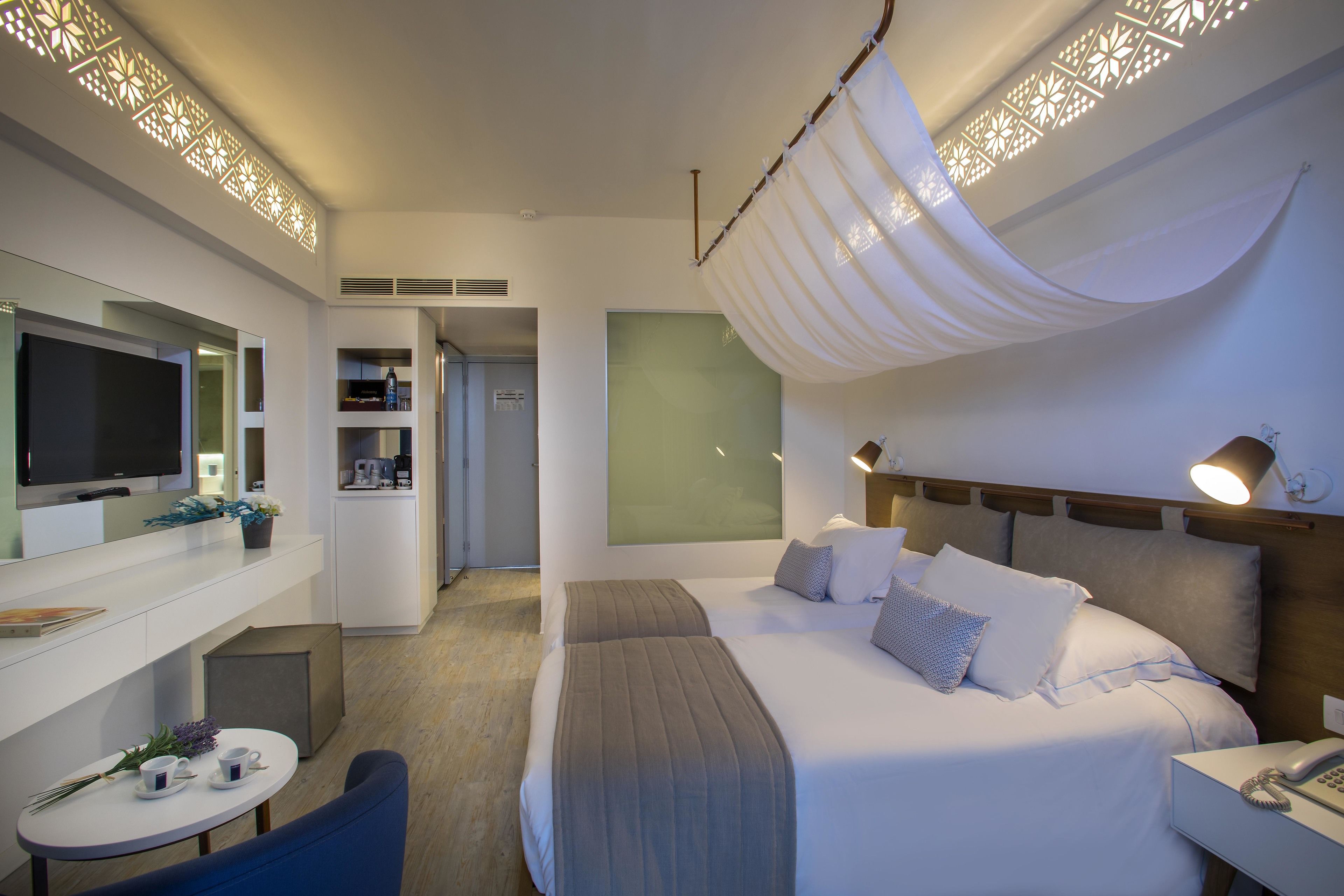 Una habitación de hotel moderna con cama, mesita de noche, lámpara y televisión.