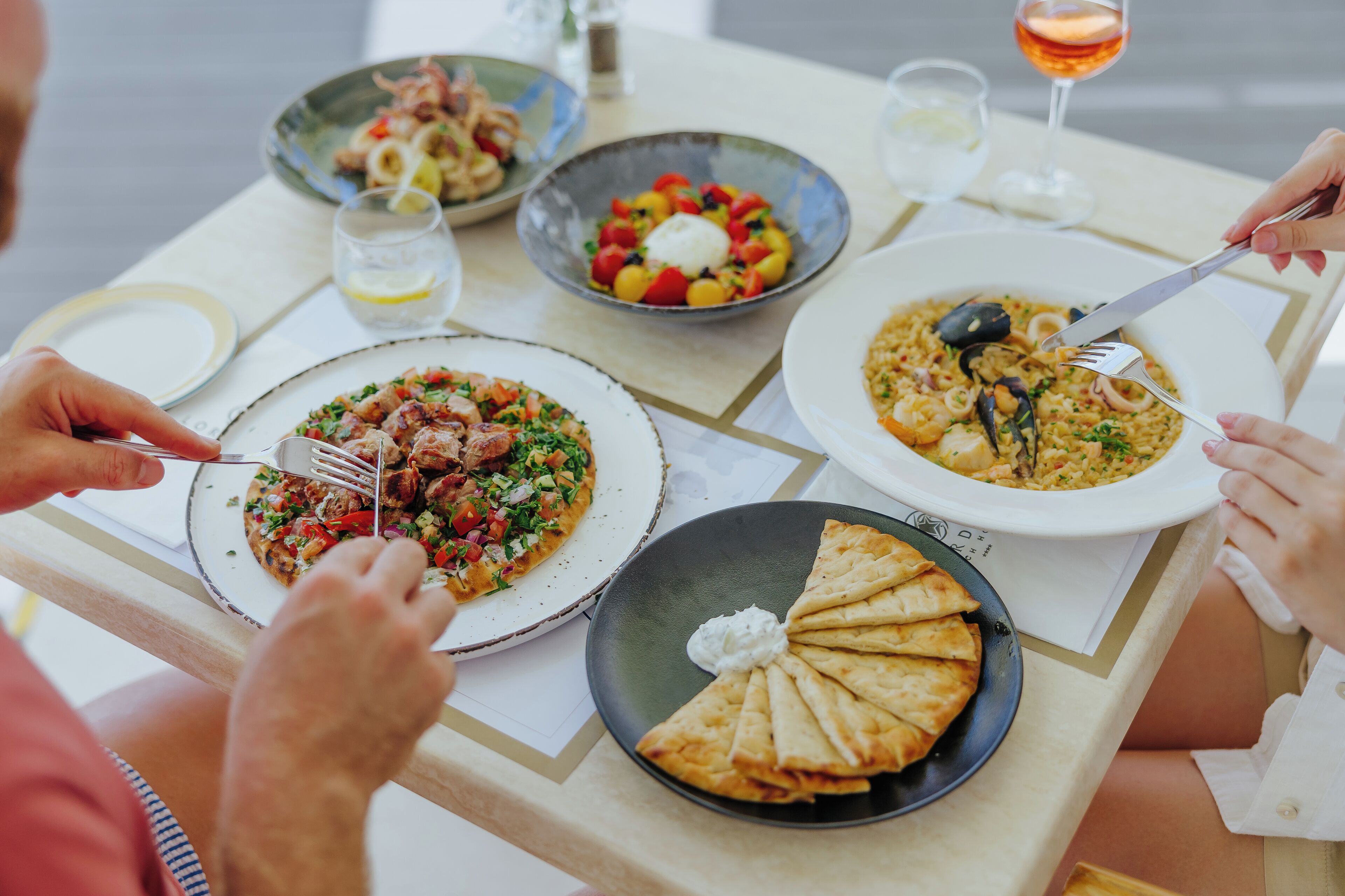 A dining table with various dishes, including seafood, vegetables, and flatbread.