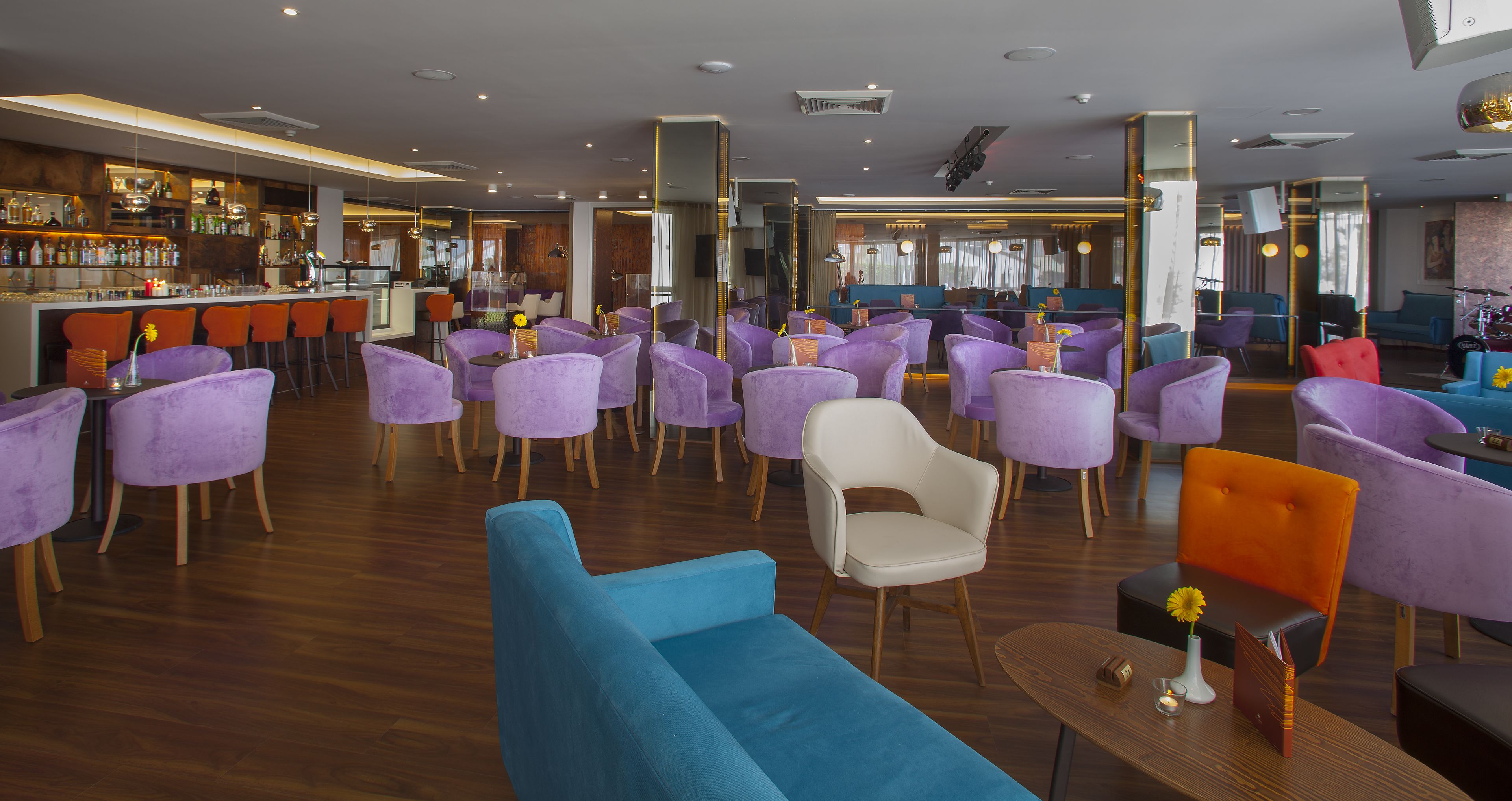 Hall dell'hotel moderno con sedute viola e blu, un'area bar e una reception.