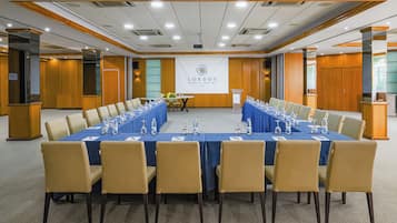 A conference room with a long table, chairs, and a podium.