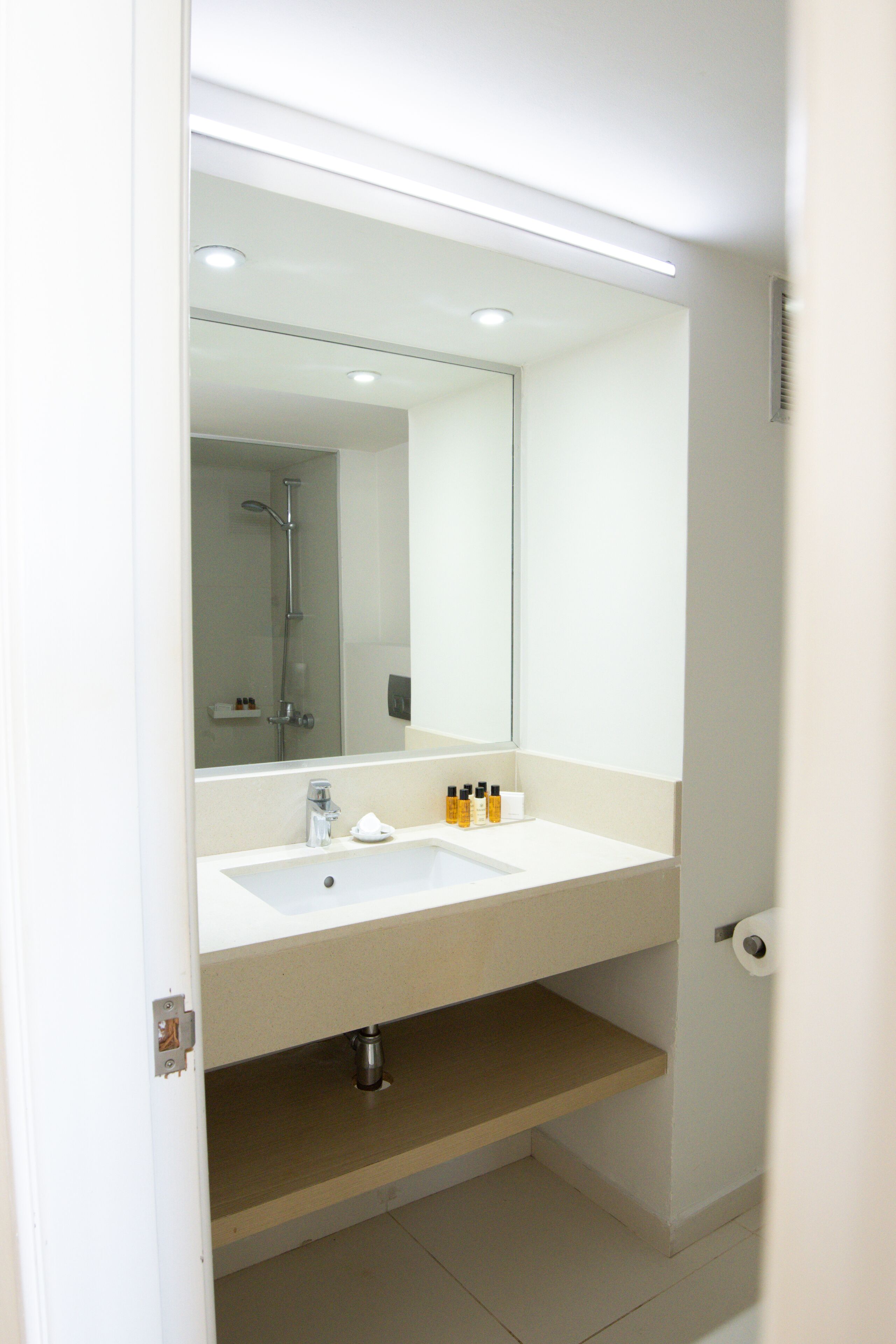 Un baño moderno con lavamanos, espejo y ducha blancos.
