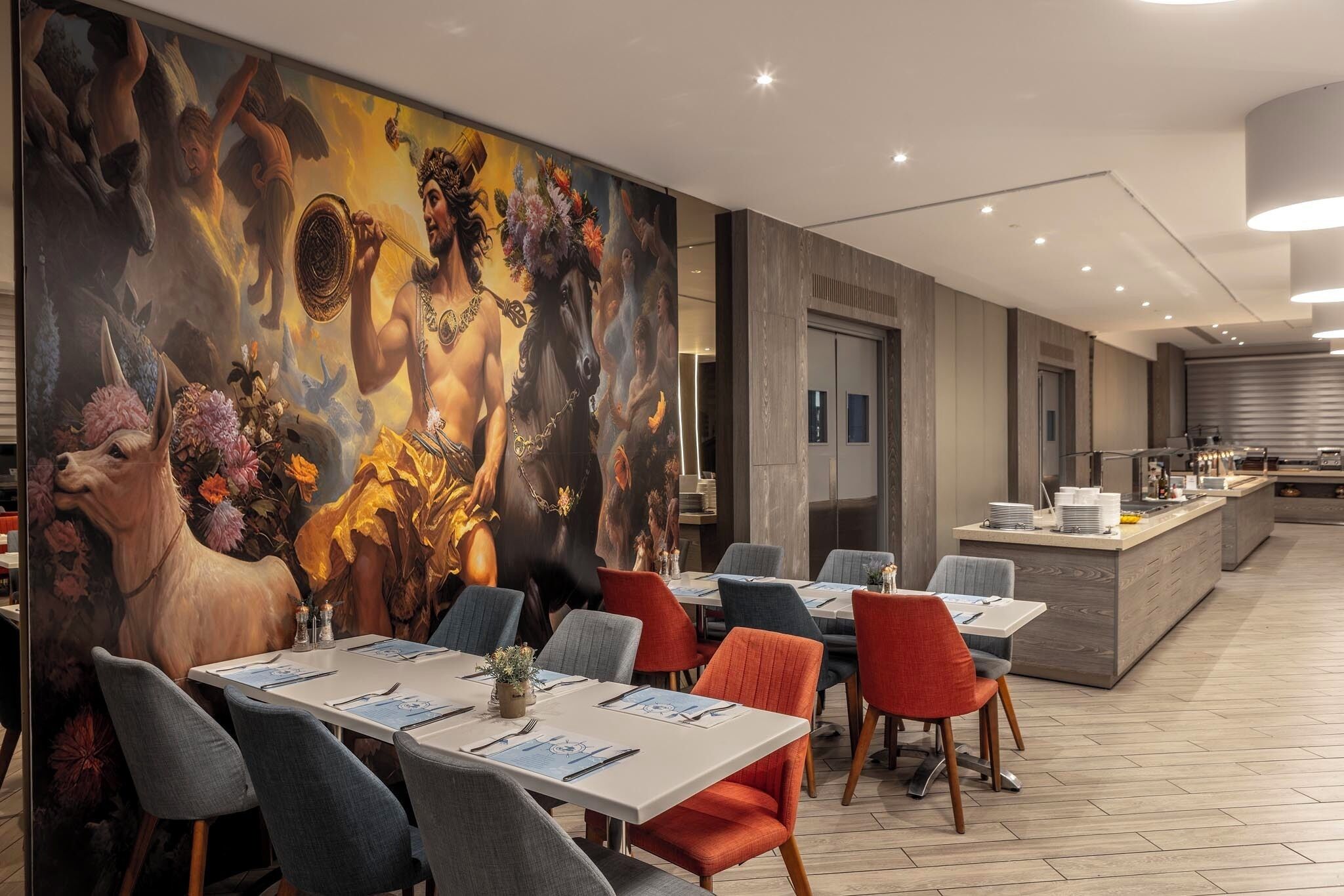 Un comedor moderno con un mural, mesas, sillas y una cocina al fondo.