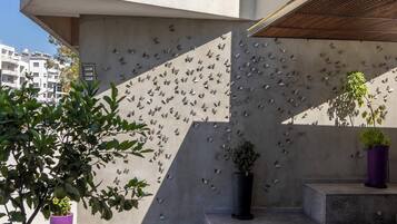A modern building facade with a butterfly wall art installation and potted plants.