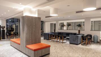 Een moderne lobby met een zithoek, banken en een groot raam.