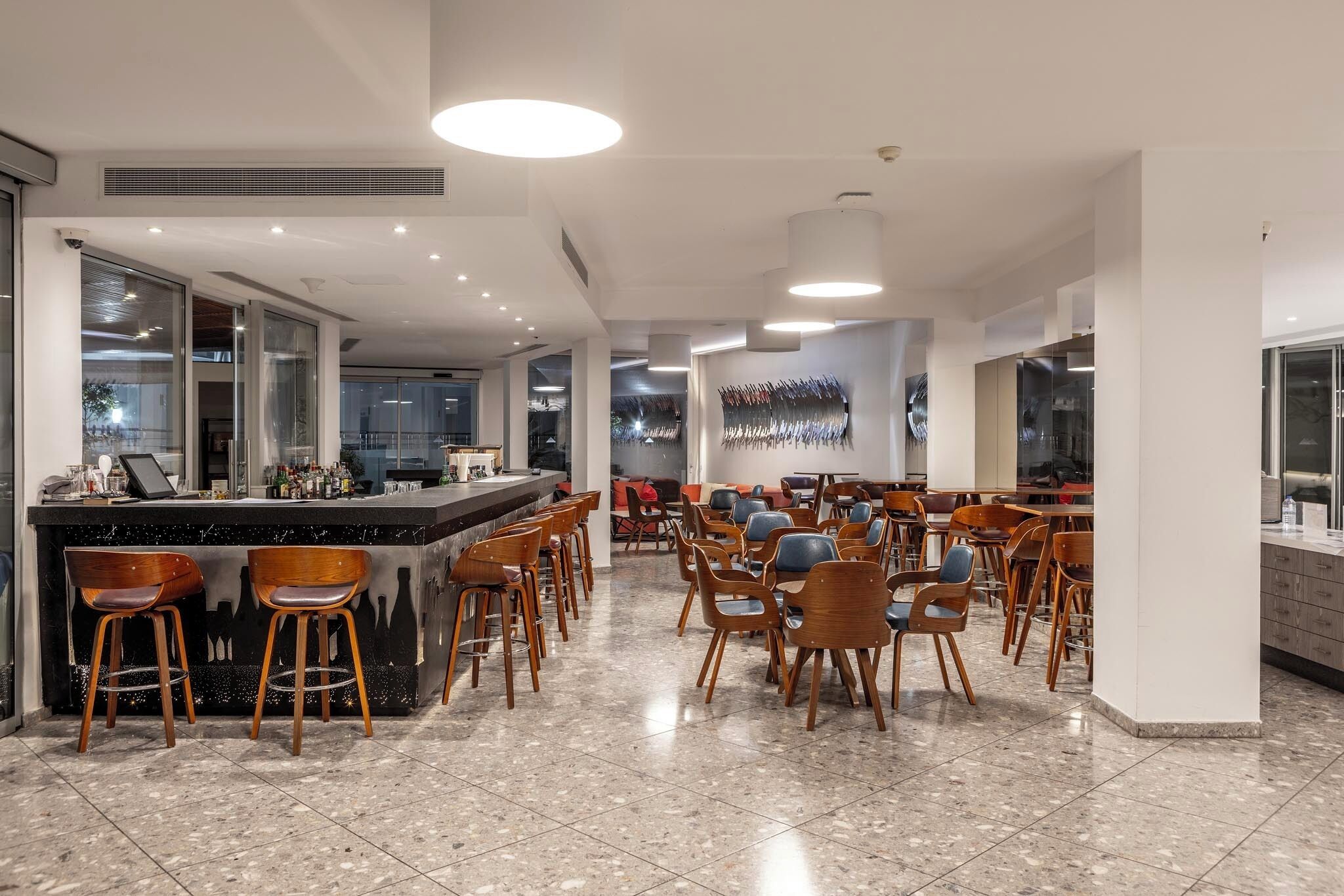 A modern restaurant with a bar area, multiple seating arrangements, and a contemporary interior design.