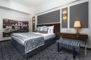 Relax in a stylish room with a large bed, bench, and wall-mounted light fixture.