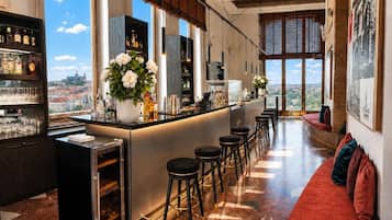 Espaço de bar com vista para a cidade, balcão, banquetes e adega de vinhos.