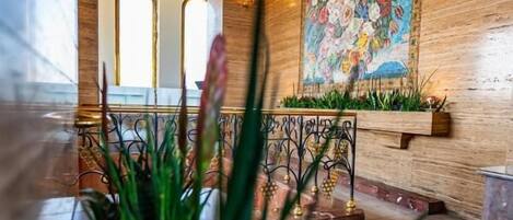 Un vestíbulo con techo de madera, un gran mural floral y una planta en primer plano.