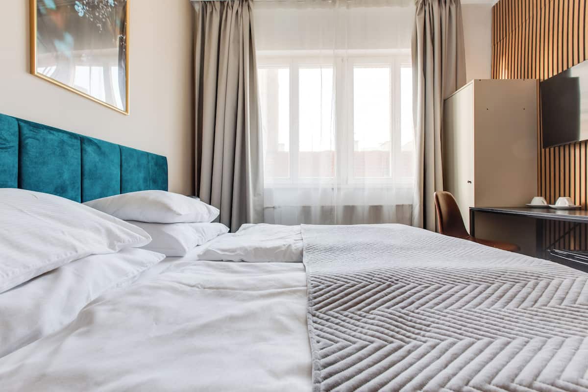 A neatly made bed with white linens, a teal headboard, and a geometric-patterned blanket.