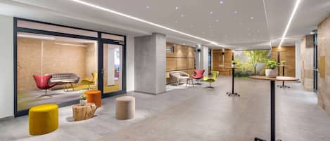A modern lobby with a spacious layout, featuring a mix of seating areas, a reception desk, and natural light from large windows.
