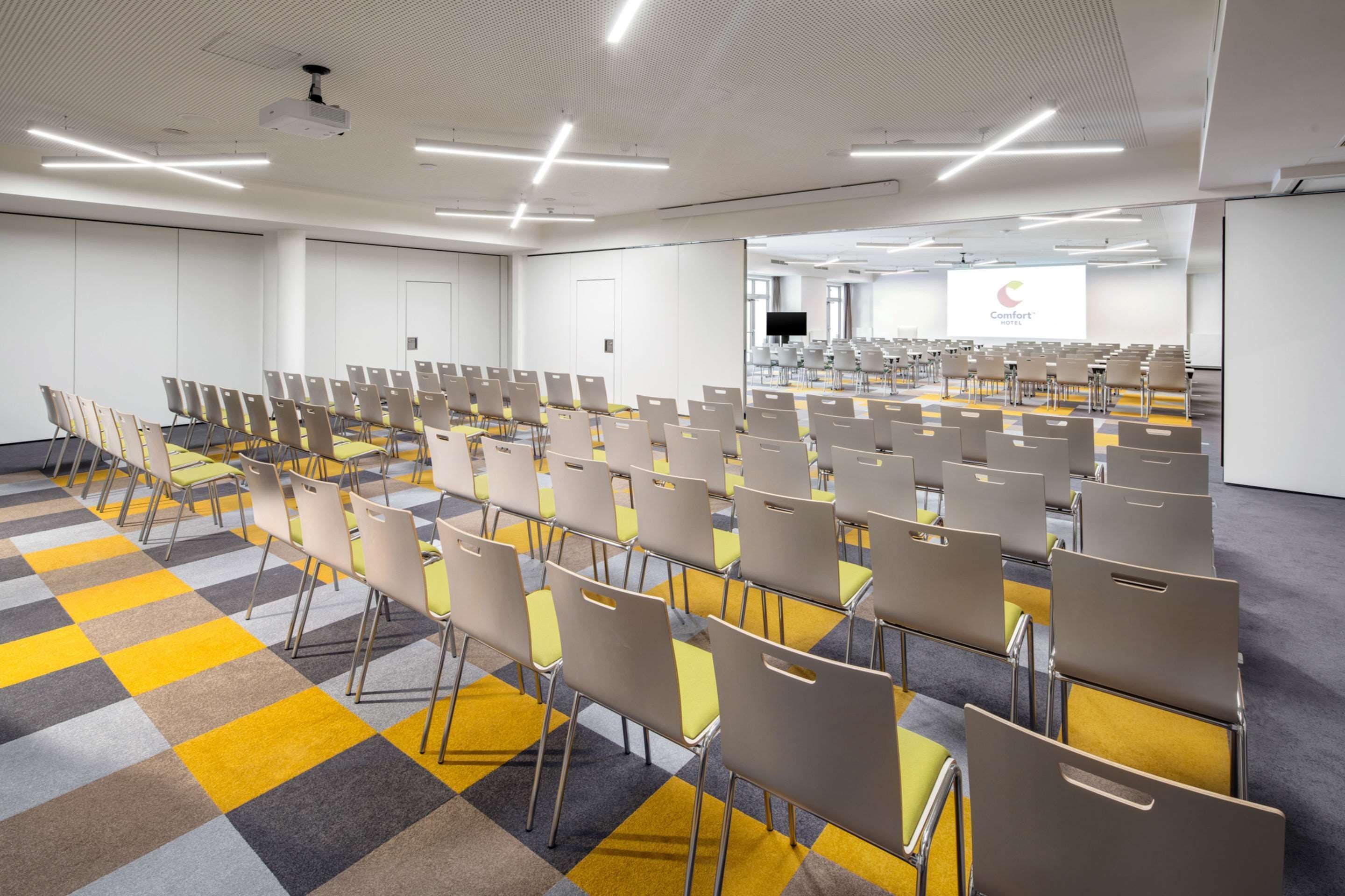 Una sala de conferències amb files de cadires, un projector i una pantalla que mostra un logotip.