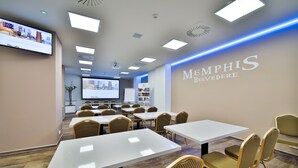 A conference room with white tables and wicker chairs, a large screen, and a projection screen. - Hotel Belvedere (Prague)