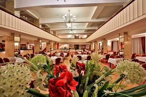 Experience the grandeur of our lobby, featuring a high ceiling, chandelier, and comfortable seating area with round tables.