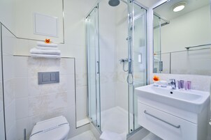 Un bagno moderno con doccia vetrata, un lavandino bianco con articoli da toilette e un water con funzione bidet.