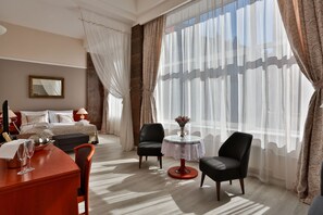 Relax in a stylishly designed room with a comfortable seating area, neatly made bed, and large window.