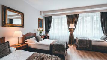 A hotel room with two beds, a desk, a chair, a lamp, and a large window with curtains.
